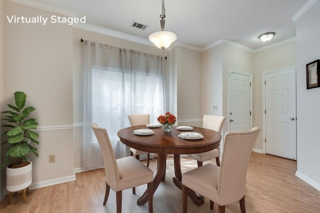 dining space with ornamental molding and light wood-type flooring