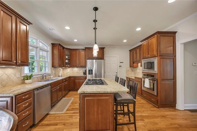 kitchen featuring stainless steel appliances, ornamental molding, a sink, a kitchen breakfast bar, and a center island