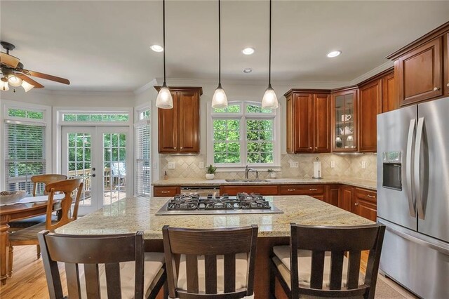 kitchen featuring appliances with stainless steel finishes, crown molding, a kitchen bar, french doors, and light stone counters