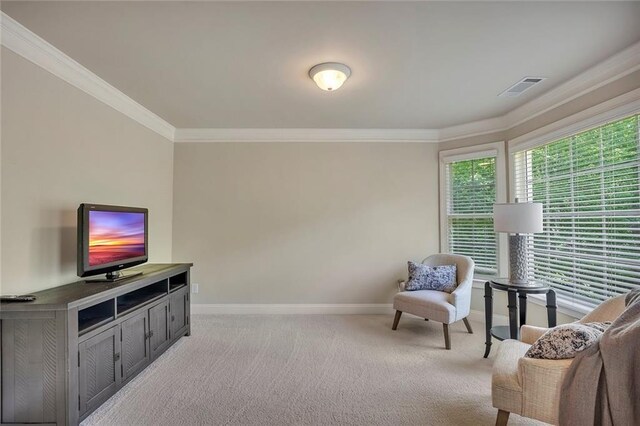 sitting room with baseboards, light carpet, and crown molding