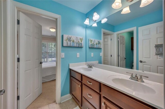 ensuite bathroom with double vanity, baseboards, and tile patterned flooring