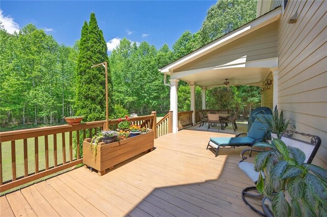 wooden terrace featuring outdoor dining area and ceiling fan
