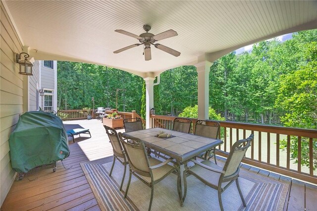 deck with outdoor dining space, a ceiling fan, and area for grilling
