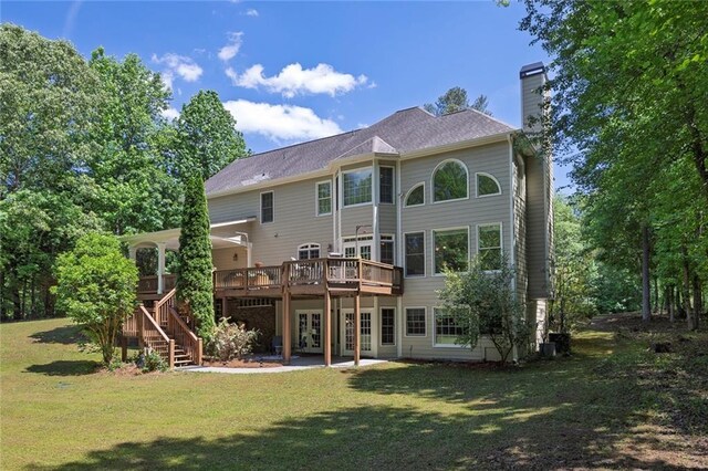 rear view of house featuring a deck, french doors, a chimney, and a yard