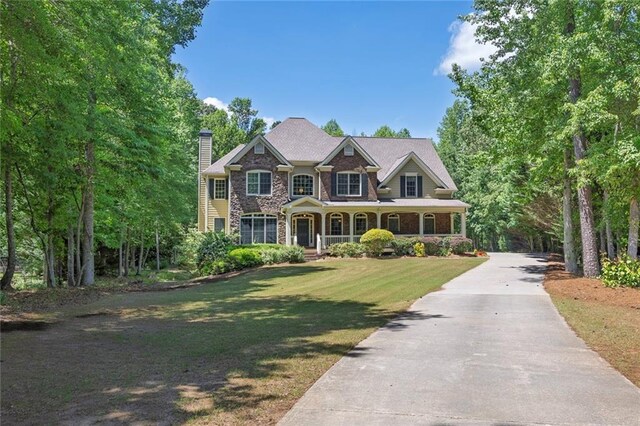 view of front of home with a chimney, a front yard, driveway, and a porch