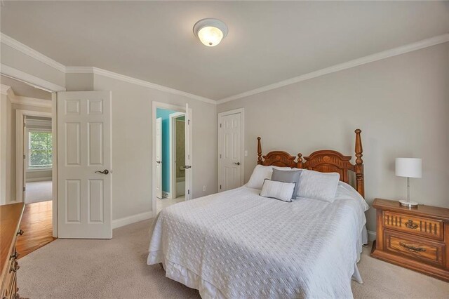 bedroom featuring crown molding, light colored carpet, baseboards, and connected bathroom