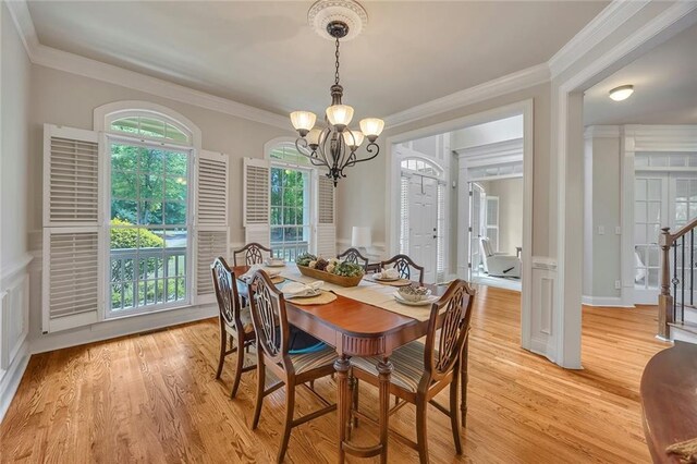 dining space with a chandelier, light wood-style floors, and ornamental molding