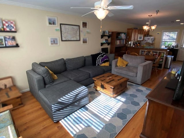 living room with crown molding, wood-type flooring, and ceiling fan with notable chandelier