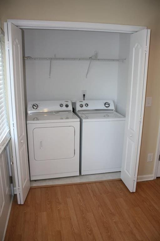 clothes washing area featuring light wood-type flooring and washer and clothes dryer