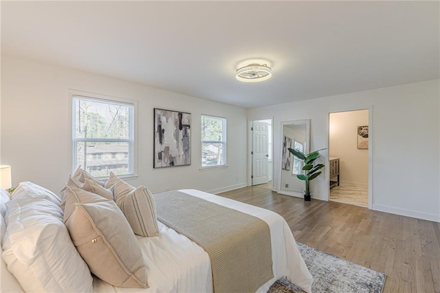 bedroom featuring light hardwood / wood-style flooring, multiple windows, and ensuite bathroom