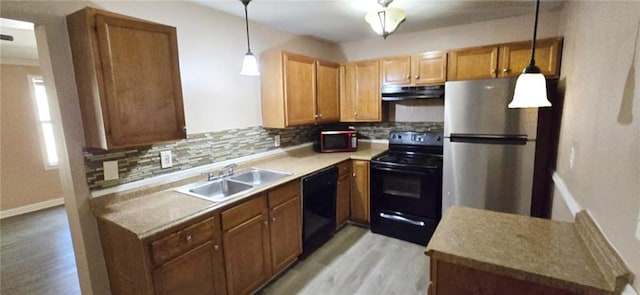 kitchen featuring sink, pendant lighting, black appliances, and light hardwood / wood-style flooring