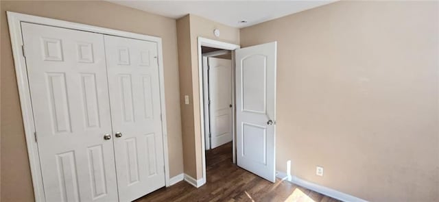 unfurnished bedroom featuring dark wood-type flooring and a closet