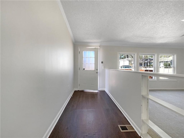 doorway to outside featuring baseboards, visible vents, wood finished floors, crown molding, and a textured ceiling