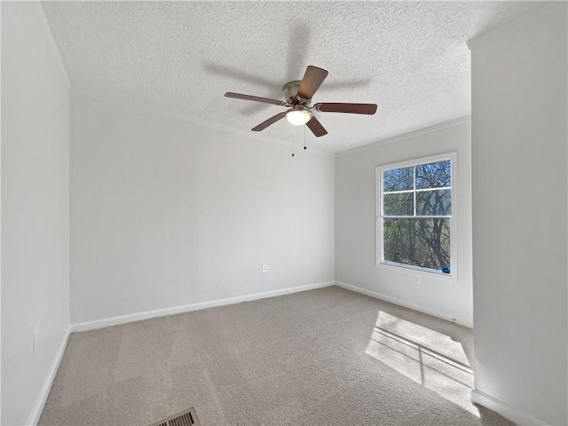 empty room with a textured ceiling, carpet, a ceiling fan, and baseboards