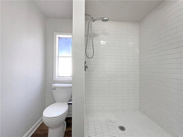 bathroom with toilet, a stall shower, and baseboards