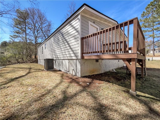 view of property exterior with central AC unit, a lawn, and a wooden deck