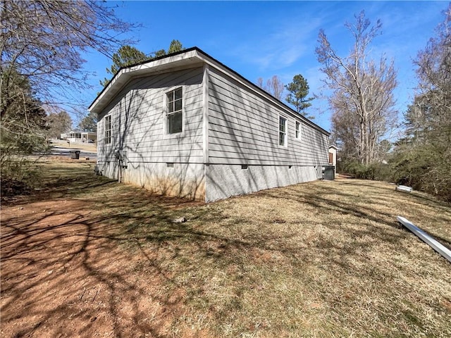 view of side of home with crawl space and a lawn