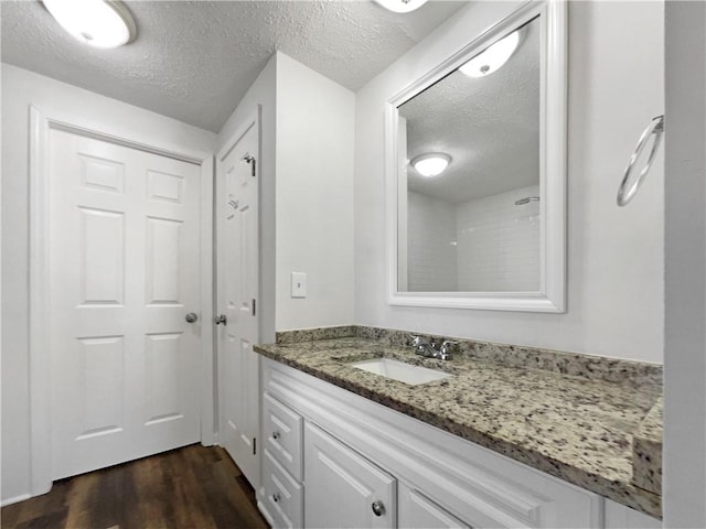 bathroom with a textured ceiling, wood finished floors, and vanity