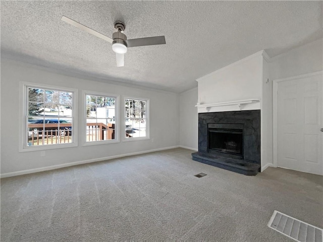 unfurnished living room with a fireplace with raised hearth, ceiling fan, carpet, and visible vents