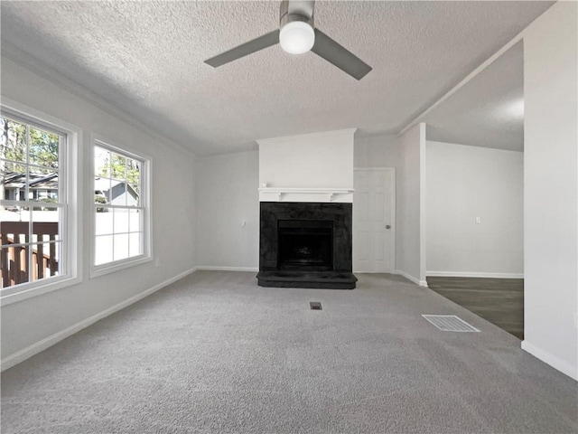 unfurnished living room featuring a fireplace, carpet flooring, visible vents, baseboards, and a ceiling fan