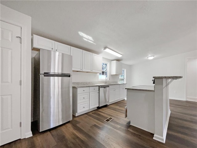 kitchen featuring appliances with stainless steel finishes, white cabinets, dark wood finished floors, and a sink