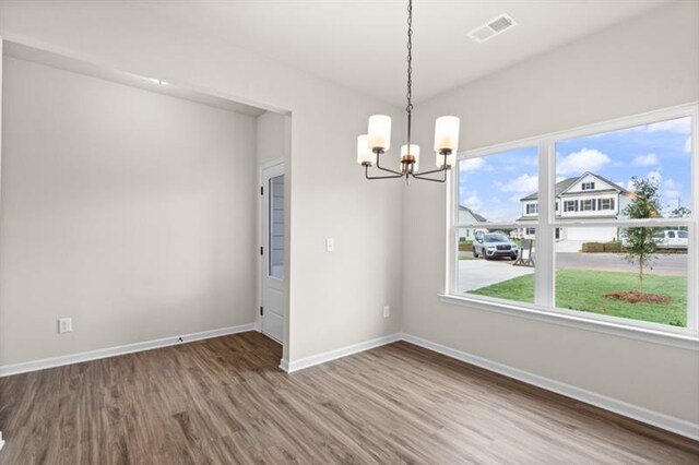 unfurnished dining area with hardwood / wood-style floors and an inviting chandelier