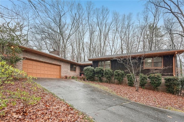 view of front facade featuring brick siding, aphalt driveway, a garage, and a chimney