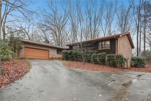 view of front facade featuring aphalt driveway, a garage, and a chimney