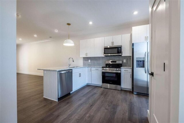 kitchen with white cabinets, appliances with stainless steel finishes, decorative light fixtures, and dark wood-type flooring