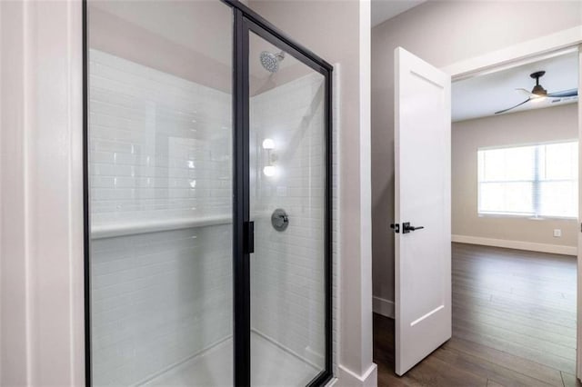 bathroom with ceiling fan, a shower with shower door, and hardwood / wood-style flooring