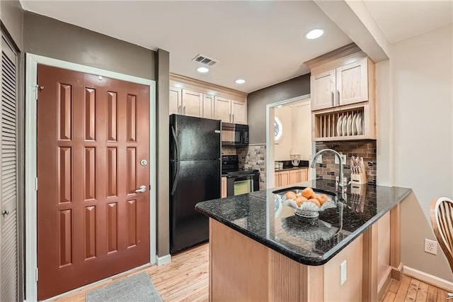 kitchen with light wood finished floors, dark stone countertops, visible vents, black appliances, and a peninsula