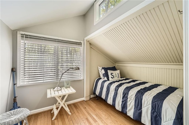 bedroom featuring light wood finished floors, vaulted ceiling, and baseboards