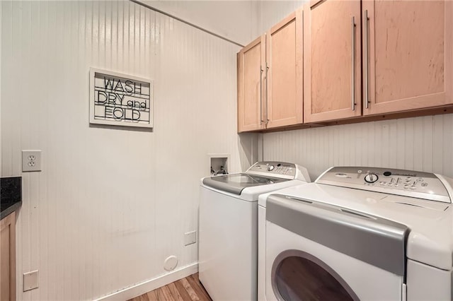 clothes washing area featuring baseboards, washer and clothes dryer, light wood-style floors, and cabinet space