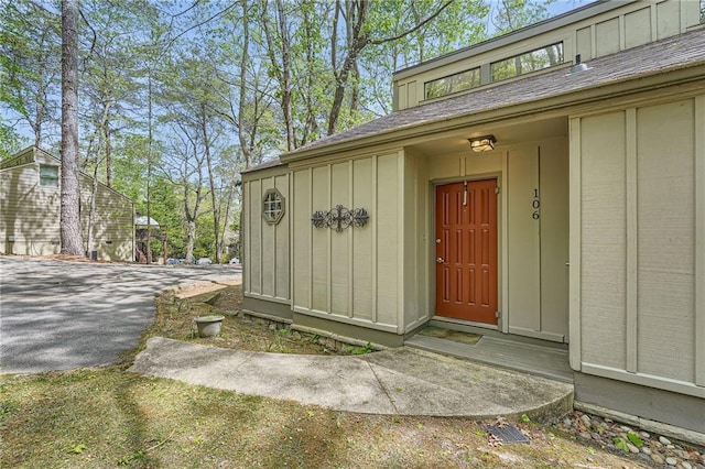 entrance to property featuring roof with shingles and board and batten siding