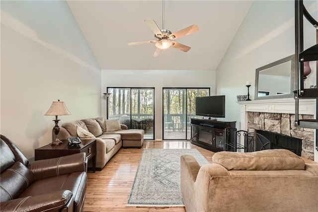 living room with a fireplace, light wood finished floors, high vaulted ceiling, and ceiling fan