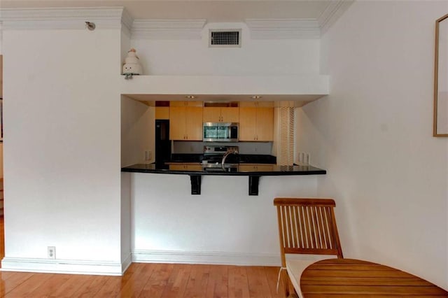 3481 Lakeside Dr NE Unit 902, Atlanta, GA 30326 - kitchen featuring appliances with stainless steel finishes, light wood finished floors, ornamental molding, a breakfast bar area, and dark countertops