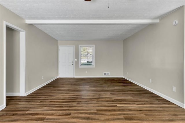 unfurnished room featuring dark wood-type flooring, a textured ceiling, and beam ceiling