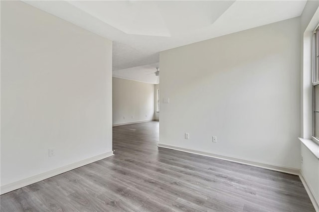 empty room featuring a ceiling fan, a healthy amount of sunlight, baseboards, and wood finished floors