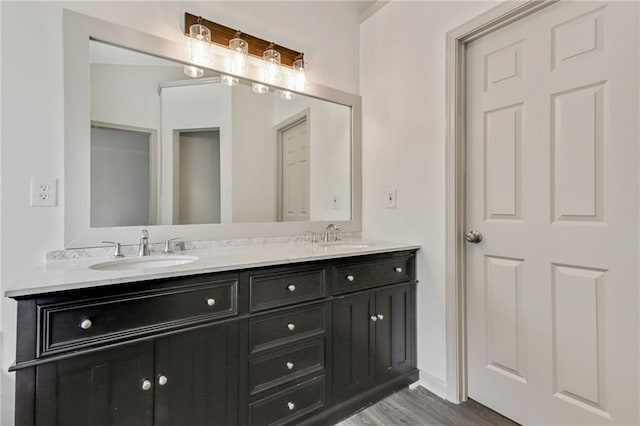 full bath with double vanity, a sink, and wood finished floors