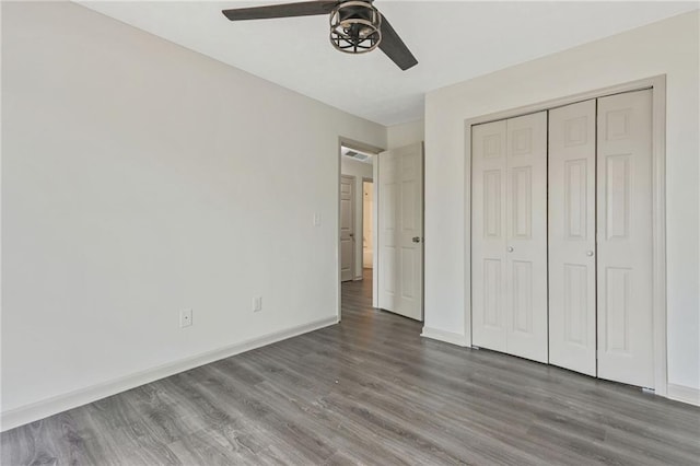 unfurnished bedroom featuring dark wood-style flooring, a closet, visible vents, a ceiling fan, and baseboards