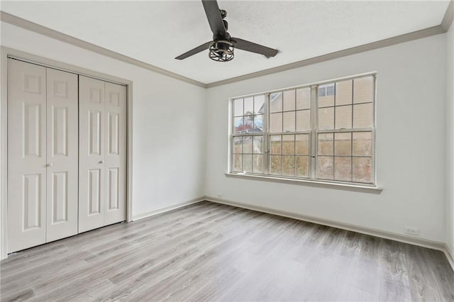 unfurnished bedroom with a closet, ornamental molding, a ceiling fan, light wood-type flooring, and baseboards