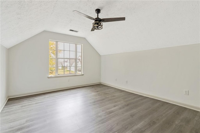 bonus room featuring visible vents, ceiling fan, wood finished floors, vaulted ceiling, and a textured ceiling