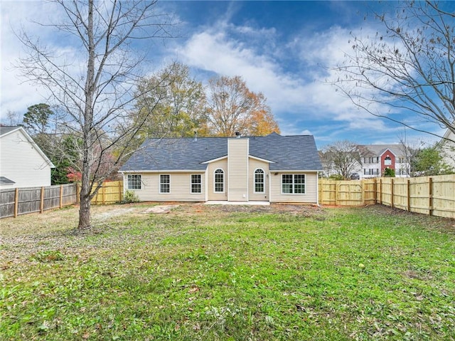 back of property with a fenced backyard, a lawn, and a chimney