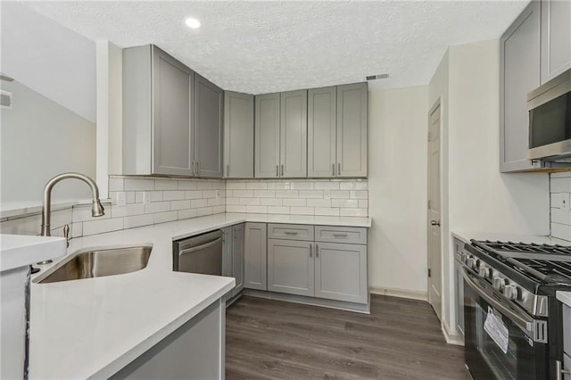 kitchen with dark wood-style flooring, light countertops, gray cabinetry, appliances with stainless steel finishes, and a sink