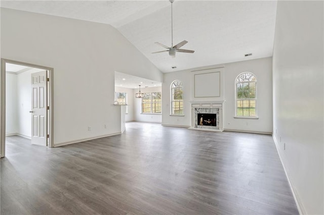 unfurnished living room with ceiling fan, wood finished floors, a high end fireplace, and a healthy amount of sunlight