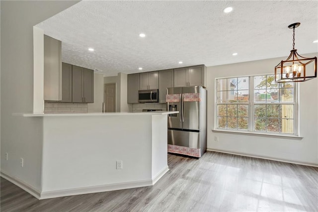 kitchen featuring appliances with stainless steel finishes, gray cabinets, light countertops, and backsplash