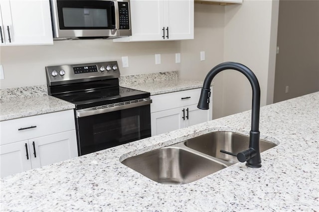 262 Stephens Rd, Cedartown, GA 30125 - kitchen with stainless steel appliances, a sink, white cabinets, and light stone counters