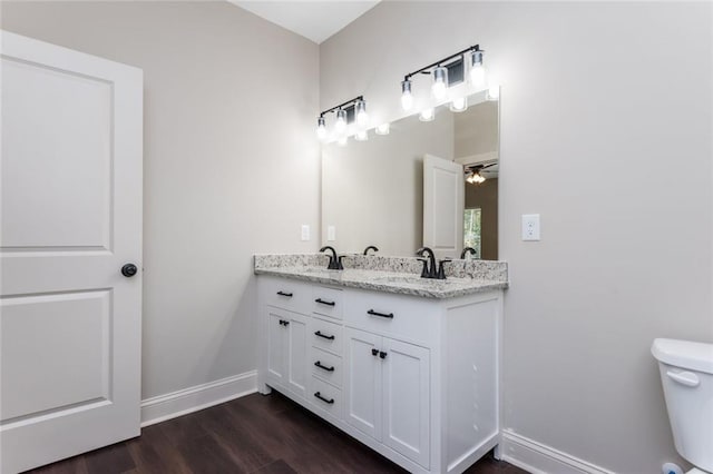 262 Stephens Rd, Cedartown, GA 30125 - full bathroom with baseboards, toilet, double vanity, wood finished floors, and a ceiling fan