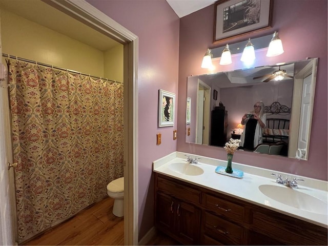 full bathroom with wood finished floors, toilet, double vanity, and a ceiling fan