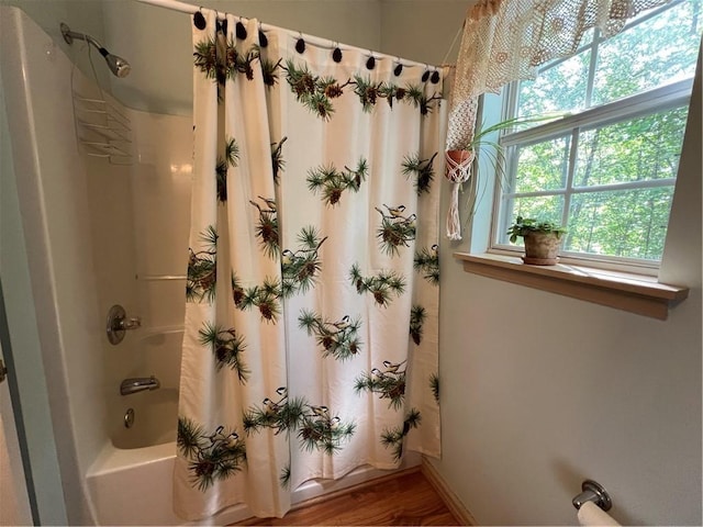 bathroom with shower / tub combo, wood finished floors, and baseboards